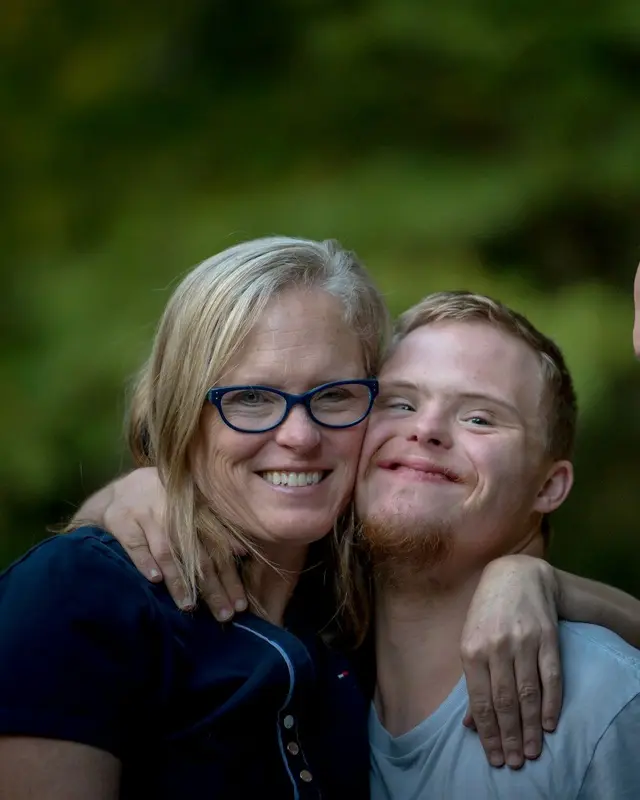 A smiling mother with her arm around her adult son