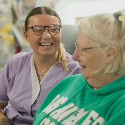 A support worker and an older woman sharing a laugh