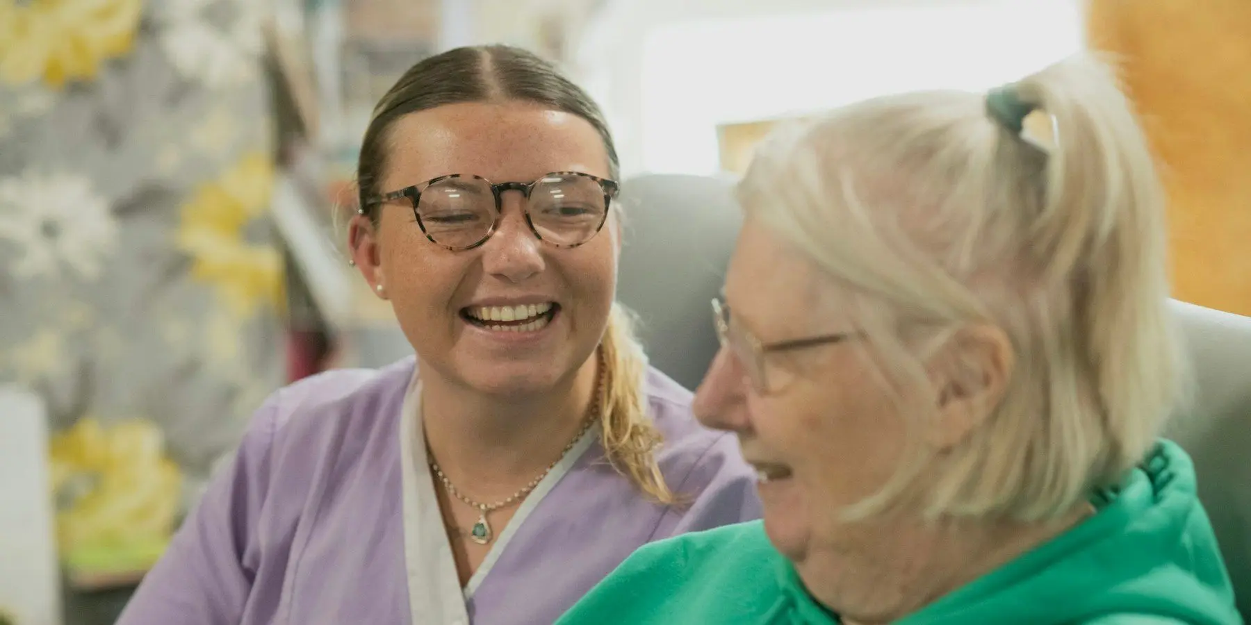 A support worker and an older woman laughing together at home